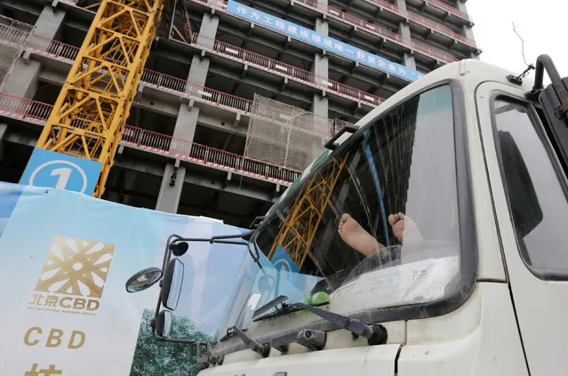 A driver rests in a construction engineering vehicle next to a construction site in Beijing's central business district, China, July 15, 2016. (Photo by Jason Lee/Reuters)