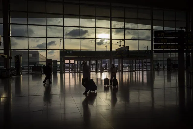 Passengers walk in an empty terminal at the airport of Barcelona, Spain, Thursday, March 19, 2020. (Photo by Emilio Morenatti/AP Photo)