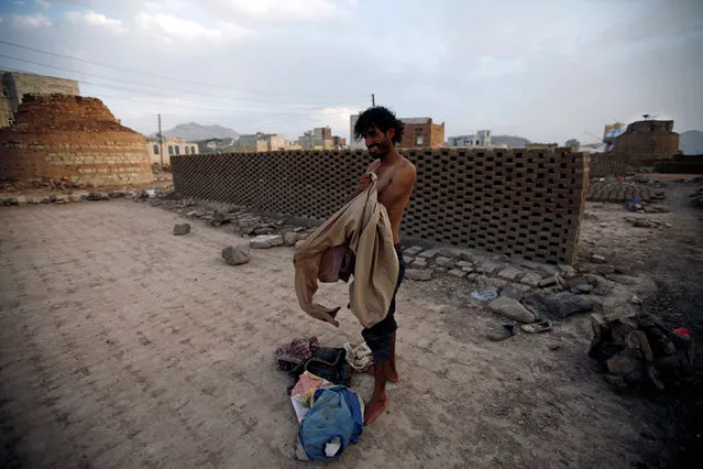 A labourer puts on his clothes at a brick factory on the outskirt of Sanaa, Yemen June 1, 2016. (Photo by Mohamed al-Sayaghi/Reuters)