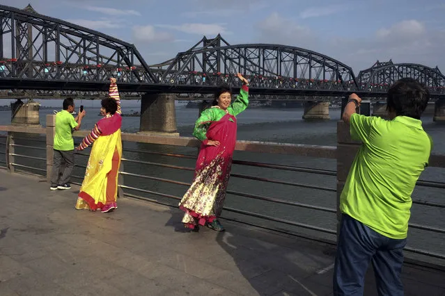 In this Tuesday, September 5, 2017 photo, Chinese tourists in North Korean costumes pose for souvenir photos near the Friendship Bridge connecting China and North Korea in the Chinese border town of Dandong, opposite side of the North Korean town of Sinuiju. Rising international tensions over Pyongyang's missile launches and nuclear tests seem a distant concern in the Chinese border city of Dandong, where trucks rumble across the bridge to North Korea and people stroll the promenade beside the Yalu River within sight of North Korean border guards. (Photo by Helene Franchineau/AP Photo)