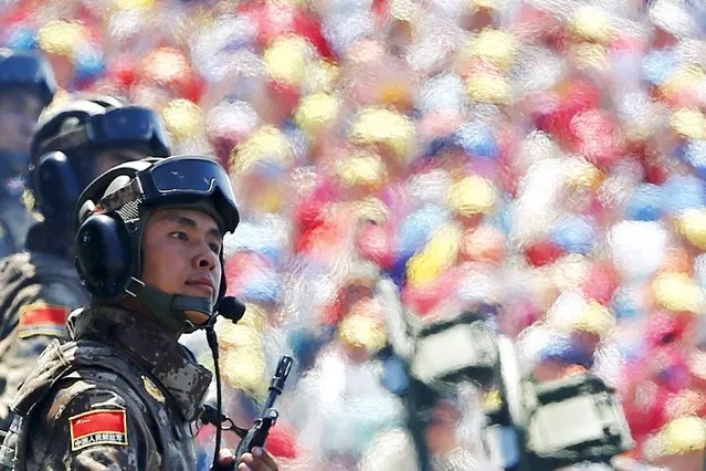 Spectators are seen through engine fumes and heat as soldiers of the People's Liberation Army (PLA) of China arrive at Tiananmen Square during the military parade marking the 70th anniversary of the end of World War Two, in Beijing, China, September 3, 2015. (Photo by Damir Sagolj/Reuters)