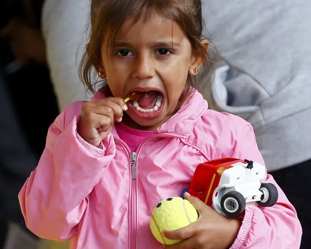 A young migrant girl enjoys a lollypop after arriving at a railway station in Vienna, Austria September 6, 2015. (Photo by Dominic Ebenbichler/Reuters)