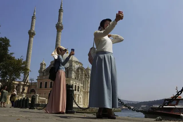 Women take photos outside from the Ortakoy Mosque at the sea side of Istanbul, on Monday, August 1, 2016. Turkey slammed a German court decision that prevented President Recep Tayyip Erdogan from addressing a demonstration in Germany denouncing Turkey's failed July 15 coup, and summoned a German diplomat in protest. (Photo by Petros Karadjias/AP Photo)