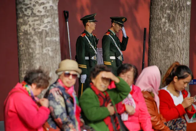 Paramilitary police officers keep watch as tourists sit near the wall surrounding the Forbidden City in Beijing, China, October 12, 2017. (Photo by Thomas Peter/Reuters)