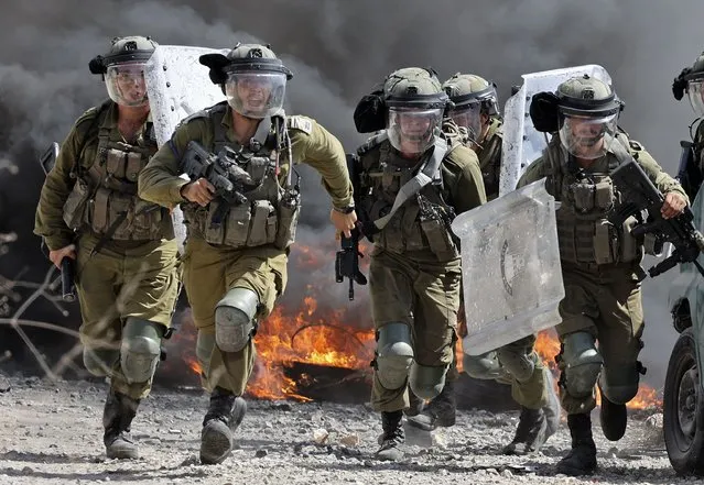 Israeli security forces run towards Palestinian demonstrators during clashes following a protest against the expropriation of Palestinian land by Israel in the village of Kfar Qaddum in the occupied West Bank near the Jewish settlement of Kedumim, on September 23, 2022. (Photo by Jaafar Ashtiyeh/AFP Photo)