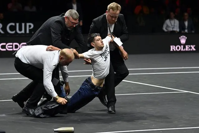 A protester is removed after invading the court, wearing a slogan 'End UK Private Jets' during the singles game between Greece's Stefanos Tsitsipas of Team Europe and Argentina's Diego Schwartzman of Team World at the 2022 Laver Cup at the O2 Arena in London on September 23, 2022. (Photo by Glyn Kirk/AFP Photo)