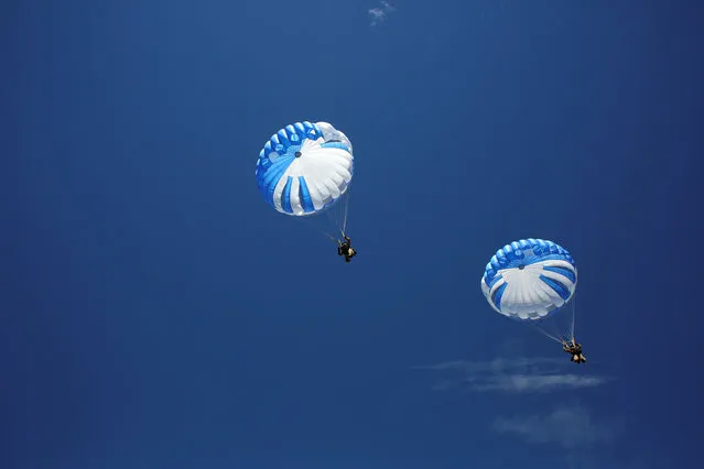 Smokejumpers navigate towards the ground after leaping from an airplane during a training exercise in Winthrop, Washington, U.S., June 6, 2016. (Photo by David Ryder/Reuters)