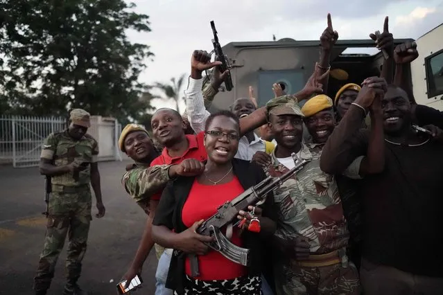 People and soldiers celebrate after the resignation of Zimbabwe' s president on November 21, 2017 in Harare. Car horns blared and cheering crowds raced through the streets of the Zimbabwean capital Harare as news spread that President Robert Mugabe, 93, had resigned after 37 years in power. (Photo by Marco Longari/AFP Photo)