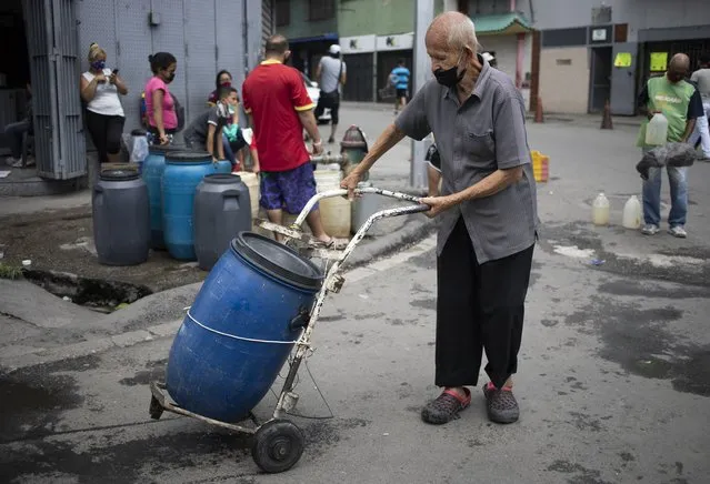 A man, wearing a protective face mask, pushes a container filled with water he collected from a street faucet on a dolly, in Caracas, Venezuela, Saturday, June 20, 2020, during a relaxation of restrictive measures amid the new coronavirus pandemic. (Photo by Ariana Cubillos/AP Photo)
