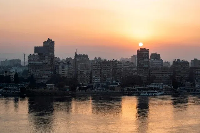The sun rises behind the skyline of Egypt's capital Cairo and its Nile river island of Manial on November 3, 2022. (Photo by Mohammed Abed/AFP Photo)