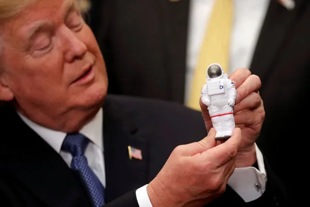 U.S. President Donald Trump holds a space astronaut toy as he participates in a signing ceremony for Space Policy Directive at the White House in Washington D.C., U.S., December 11, 2017. (Photo by Carlos Barria/Reuters)
