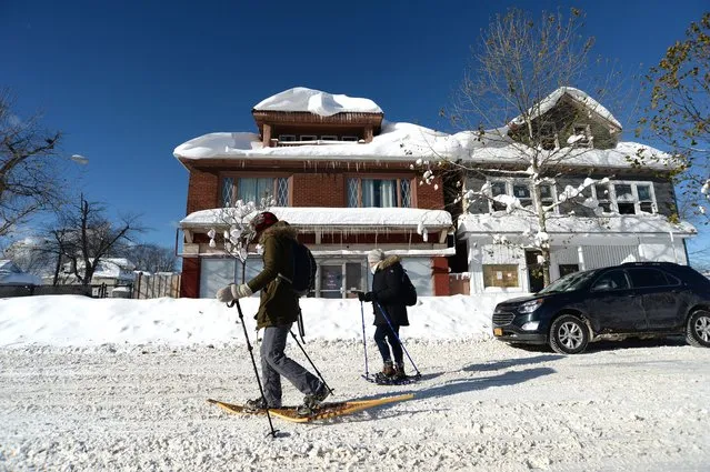 Megan Barr and Amanda Johnston snowshoe through snow covered streets after an intense lake-effect snowstorm that impacted the area on November 20, 2022 in Buffalo, New York. (Photo by John Normile/Getty Images)