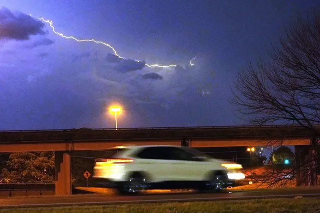 A vehicle races along a Jackson, Miss., street as lightning streaks across the sky, Tuesday evening, Noember. 29, 2022. Area residents were provided a light show as severe weather accompanied by some potential twisters affected parts of Louisiana and Mississippi. (Photo by Rogelio V. Solis/AP Photo)