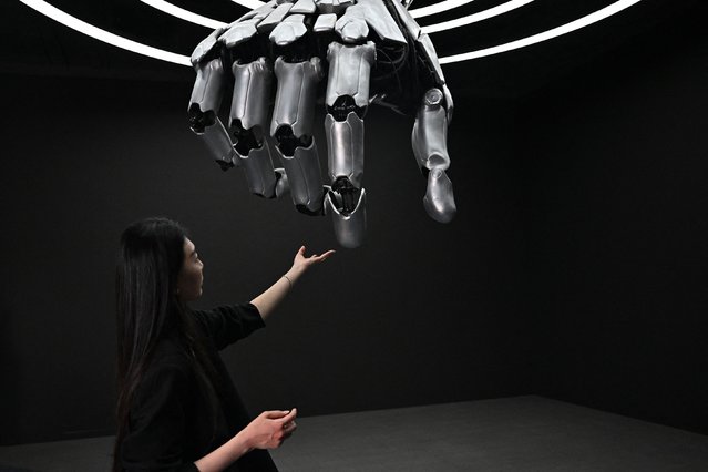 A woman touches a robotic hand during a press tour of the Beijing World of Robots exhibition center on Thursday, April 17, 2025. (Photo by AFP Photo/China Stringer Network)
