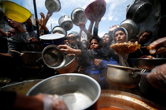 Palestinians wait to receive food cooked by a charity kitchen, in Beit Lahiya, northern Gaza Strip, on April 28, 2025. (Photo by Mahmoud Issa/Reuters)
