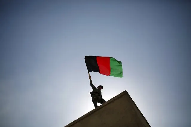 An Afghan National Army (ANA) officer holds an Afghanistan flag during a training exercise at the Kabul Military Training Centre in Afghanistan October 7, 2015. (Photo by Ahmad Masood/Reuters)
