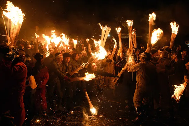 People rush forward with flaming sticks as they try to set fire to a wooden shrine that is protected by men from Nozawaonsen village during the Nozawaonsen Dosojin Fire Festival on January 15, 2018 in Nozawaonsen, Japan. The festival is staged by village men of “yakudoshi¨ or “unlucky” ages of 42 and 25 to celebrate the birth of a family's first child, to chase away evil spirits, and to pray for a happy marriage. It takes the form of fire battle between the men who build the shrine, who try to protect it, and the other villagers who try to set it aflame by throwing torches at the shrine. (Photo by Carl Court/Getty Images)