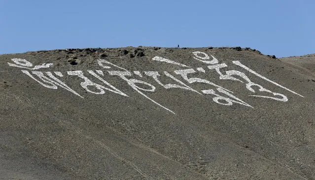 A man walks on the top of the Dogee mountain above a giant sign of a Buddhist Mantra near the town of Kyzyl, administrative centre of Tuva region, Southern Siberia, Russia, October 7, 2015. (Photo by Ilya Naymushin/Reuters)