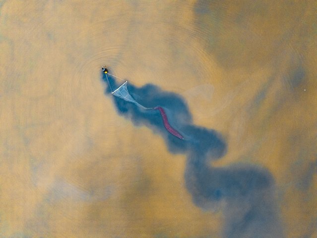 In this aerial view, a worker hauling a long net harvests brine shrimps in the Salt Lake on July 1, 2025 in Yuncheng, Shanxi Province of China. (Photo by Lan Liqiang/VCG via Getty Images)