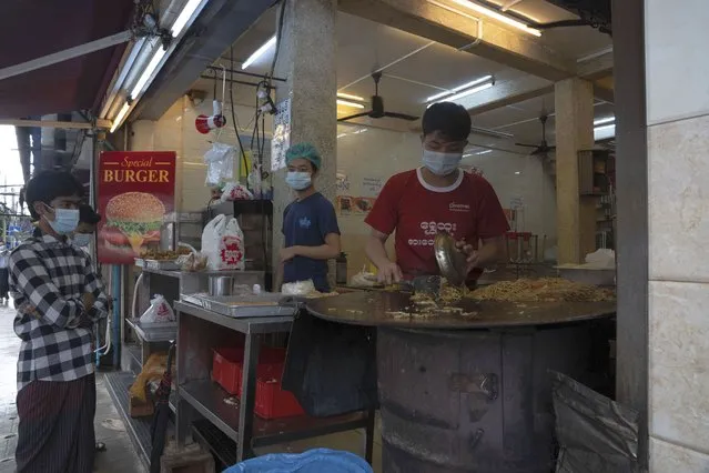 Customers wearing face masks wait for take-away meals ordered at a restaurant in Yangon, Myanmar,Monday, September 21, 2020. Myanmar, faced with a rapidly rising number of coronavirus cases and deaths, has imposed the tightest restrictions so far to fight the spread of the disease in Yangon, the country's biggest city and main transportation hub. (Photo by Pyae Sone Win/AP Photo)