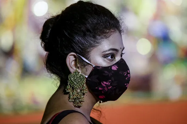 A Hindu devotee wearing face mask and ornaments visits an almost deserted worship venue of Hindu goddess Durga during Durga Puja, the biggest festival of the region, in Kolkata, India, Sunday, October 25, 2020. The Hindu festival season is traditionally laced with an unmatched fanfare and extravaganza, with socializing being the hallmark of the celebration. But because of the coronavirus pandemic this year's festivities have started on a pale note. (Photo by Bikas Das/AP Photo)