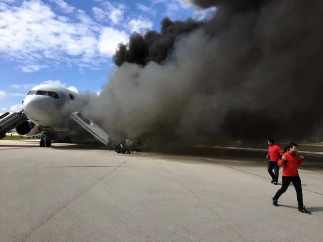 Passengers are evacuate from a plane on fire at Fort Lauderdale airport, Florida on October 29, 2015. An airliner caught fire on a runway at Fort Lauderdale in Florida Thursday and several people were injured, authorities said. "Airplane engine fire," the Broward County Sheriff's Office said on Twitter, adding: "several injuries". (Photo by Andres Gallego/AFP Photo)