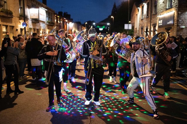 Members of “Chav Brass” band, wearing tracksuits and sportswear to imitate a type of style in the youth culture, play in the Whit Friday brass band competition in the village of Uppermill, near Oldham, northern England on May 24, 2024. Chav Brass, a scratch band which has formed for one day per year to play in the Whit Friday contests, has competed since 2007 and is made up from musicians who either play at, or who have played at, the very top level of banding. The “Saddleworth and Tameside District Whit Friday Brass Band Contests” attract approximately 100 brass bands from all over the UK and Europe to compete in around 20 villages and towns on the western edge of the Pennines. (Photo by Oli Scarff/AFP Photo)