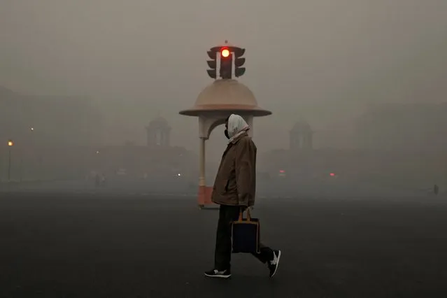 An office-goer walks past a traffic signal near various federal government ministries on a smoggy morning in New Delhi, India, November 10, 2020. (Photo by Danish Siddiqui/Reuters)