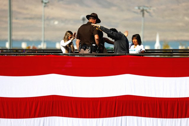 People pray around a Utah State Trooper and a big U.S. flag is displayed on campus as students return to classes at Utah Valley University following the killing of Charlie Kirk, in Orem, Utah on September 17, 2025. (Photo by Jim Urquhart/Reuters)