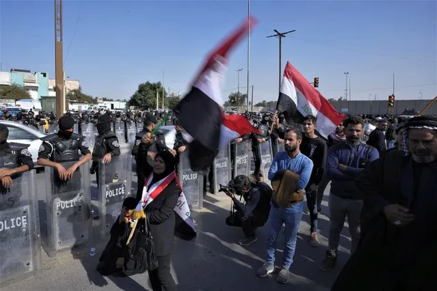 Protesters they wave Iraqi flags during protest against planned changes in electoral law, near the Iraq's parliament in Baghdad, Iraq, Monday, February 27, 2023. Hundreds of protesters took to the streets in Baghdad to voice their dissent against a draft elections law that would increase the size of the country's electoral districts. (Photo by Hadi Mizban/AP Photo)