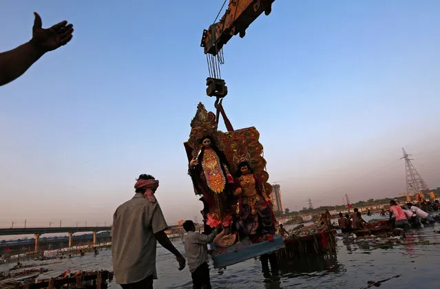 Devotees prepare to immerse an idol of the Hindu goddess Durga in the Yamuna River on the last day of the Durga Puja festival in New Delhi, India October 11, 2016. (Photo by Adnan Abidi/Reuters)