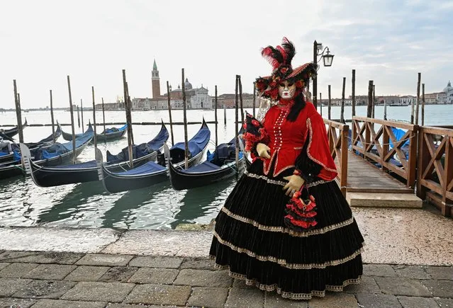 A masked reveller wearing a traditional carnival costume poses on St Mark Square, Venice on February 20, 2022, during the annual carnival. (Photo by Andrea Pattaro/AFP Photo)