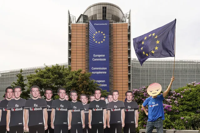 An Avaaz demonstrator waves the European flag as he stands next to life-sized Zuckerberg cutouts to protest against fake Facebook accounts spreading disinformation on the platform, near the EU Commission in Brussels, Tuesday, May 22, 2018. European Union lawmakers plan to press Facebook CEO Mark Zuckerberg on Tuesday about data protection standards at the internet giant at a hearing focused on a scandal over the alleged misuse of the personal information of millions of people. (Photo by Geert Vanden Wijngaert/AP Photo)