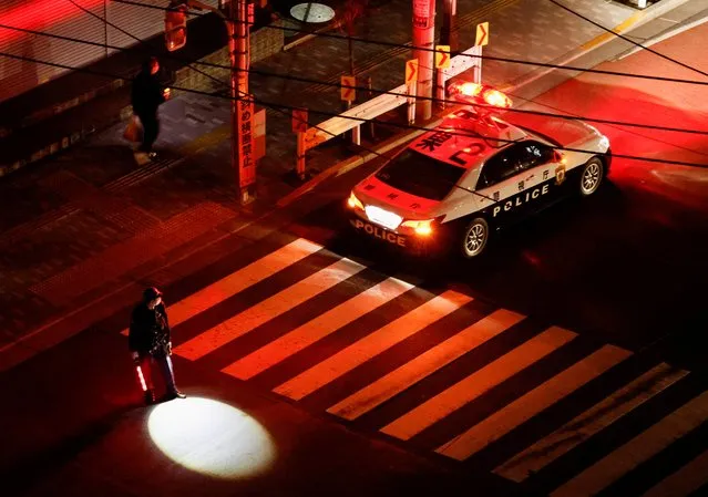 A police officer tries to control traffic on the street during an electric stoppage after an earthquake in Tokyo, Japan on March 17, 2022. (Photo by Issei Kato/Reuters)