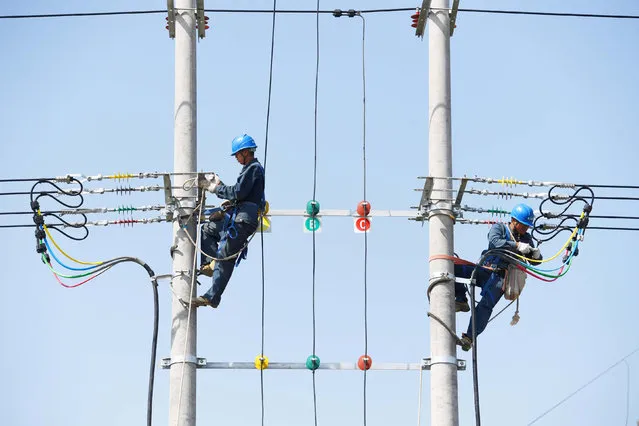 Technicians work on power cables on utility poles in Chuzhou, Anhui province, China May 10, 2018. (Photo by Reuters/China Stringer Network)