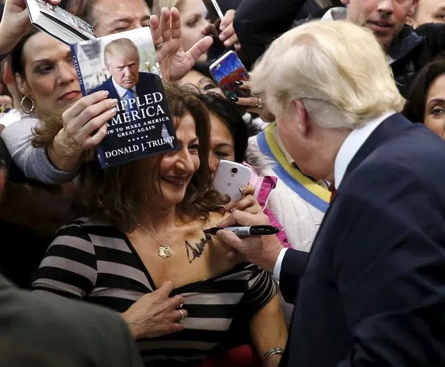 Republican presidential candidate Donald Trump (R) autographs the chest of a woman at his campaign rally in Manassas, Virginia December 2, 2015.  Republican presidential front-runner Trump said on Wednesday his plan for combating Islamic State militants involves targeting not just the group's fighters but also their families. (Photo by Gary Cameron/Reuters)