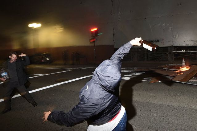 A protester throws a bottle at police officers following the election of Republican Donald Trump as President of the United States in Oakland, California, U.S. November 9, 2016. (Photo by Noah Berger/Reuters)