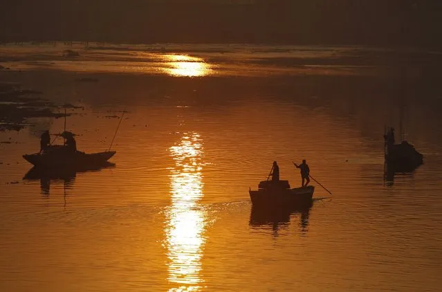 Kashmiri boatmen travel in their boats as some use shovels to extract sand from the Jhelum river as the sun rises in Srinagar January 19, 2015. (Photo by Danish Ismail/Reuters)