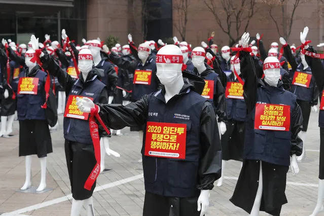 Mannequins are displayed as members of the KEB Hana Bank union stage a rally against their company's management policy in front of the bank's headquarters in Seoul, South Korea, Friday, March 12, 2021. The mannequins were used to avoid the violation of an ongoing ban on rallies with more than 10 people amid the coronavirus pandemic. The signs read: “Let's win wages through struggle, unity and fight”. (Photo by Ahn Young-joon/AP Photo)