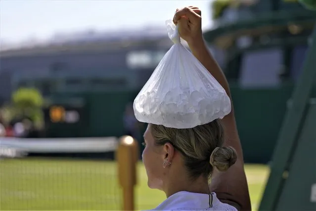 Ukraine's Marta Kostyuk places a bag of ice on her head as she tries to keep cool during a break as she plays Spain's Paula Badosa in a women's singles match on day five of the Wimbledon tennis championships in London, Friday, July 7, 2023. (Photo by Alberto Pezzali/AP Photo)