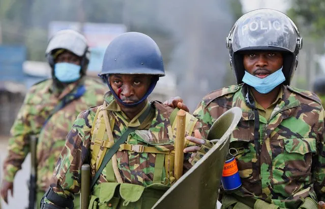 An injured riot police officer is escorted by his colleagues after a confrontation with supporters of Kenya's opposition leader Raila Odinga of the Azimio La Umoja (Declaration of Unity) One Kenya Alliance, during an anti-government protest against the imposition of tax hikes by the government, in Mathare settlement in Nairobi, Kenya on July 12, 2023. (Photo by John Muchucha/Reuters)