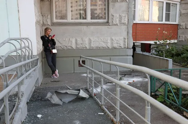 A woman checks her phone next to debris, following a reported drone attack in Krasnogorsk, Russia on August 22, 2023. Russian air defences downed two attack drones near Moscow, the city's mayor said on August 22, in the fifth consecutive night of strikes on the capital region. (Photo by Reuters/Stringer)
