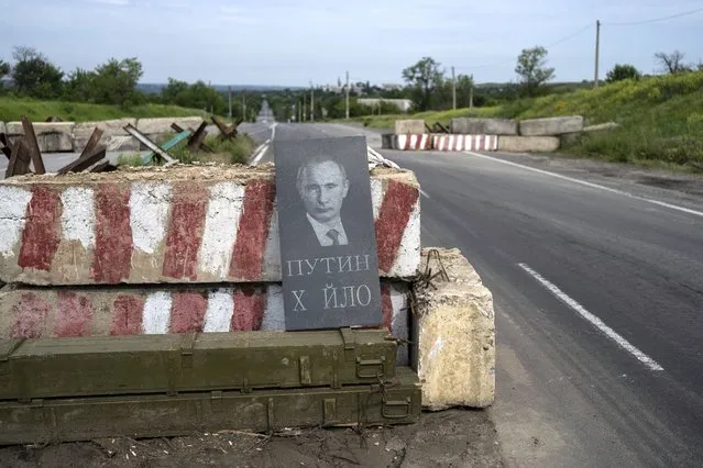A tombstone with the picture of Russian President Vladimir Putin and a derogatory message sits at a checkpoint in the Donetsk oblast region of eastern Ukraine, Sunday, June 5, 2022. The text reads “Putin dickhead”. (Photo by Bernat Armangue/AP Photo)