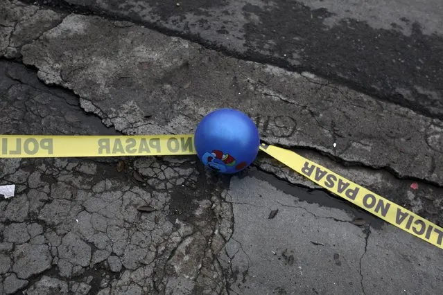 A ball is seen lying on top of a police cordon at a crime scene where a woman was shot dead at a car wash in San Salvador, September 24, 2015. (Photo by Jose Cabezas/Reuters)