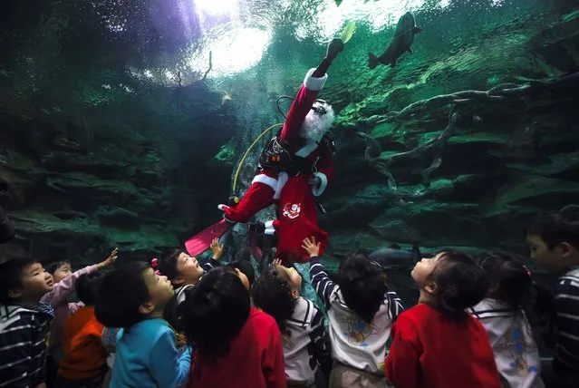 A South Korean diver wearing a Santa Claus outfit swims with fish in a tank during a Christmas event at the Lotte World Aquarium in Seoul on December 20, 2016. (Photo by Jung Yeon-Je/AFP Photo)