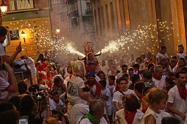 A man runs through the streets carrying a fake bull's head and horns that shoots out sparks in all directions, at the San Fermin Festival in Pamplona, northern Spain, Wednesday, July 13, 2022. (Photo by Alvaro Barrientos/AP Photo)