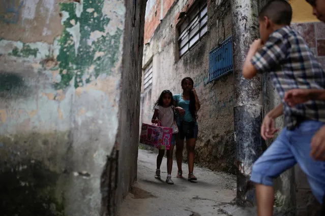 A girl walks with a toy received during a toy distribution program with Miguel Pizarro, deputy of the Venezuelan coalition of opposition parties (MUD), in an alley at the slum of Petare in Caracas, Venezuela December 20, 2016. (Photo by Marco Bello/Reuters)