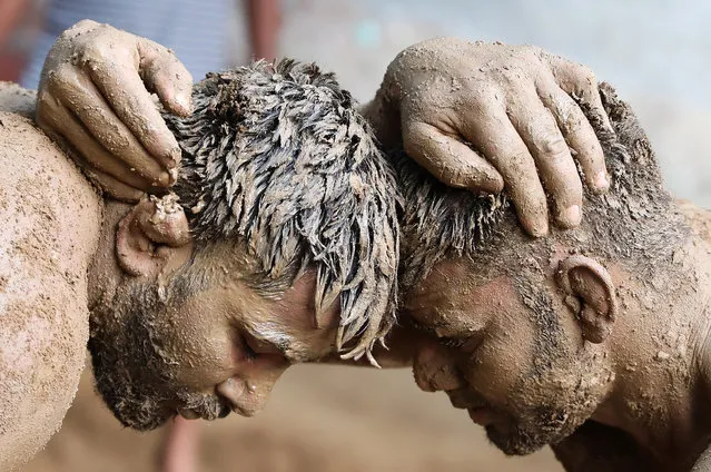 Indian traditional wrestlers put mud on each other before practicing yoga to mark the International Day of Yoga on a dirt ground at Maharishi Dayanand Akhara, a traditional wrestling school in Sarfabad, on the outskirts of New Delhi, India, 21 June 2021. In December 2014, the United Nations (UN) declared 21 June as the International Day of Yoga after adopting a resolution proposed by Indian Prime Minister Modi. (Photo by Harish Tyagi/EPA/EFE)