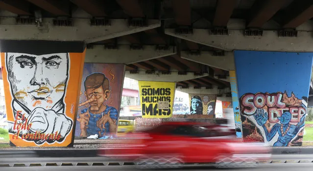 In this March 18, 2015 photo, a car speeds past backdropped by overpass supports covered with street art, in Bogota, Colombia. (Photo by Fernando Vergara/AP Photo)