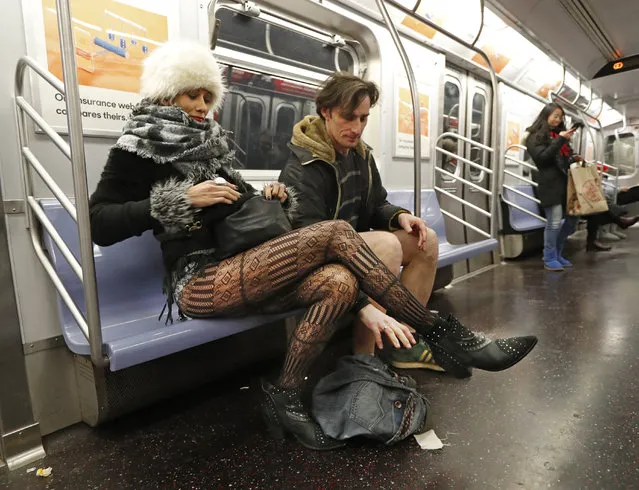 Leon Feingold, right, drops his jeans as his girlfriend Patrizia Calvio looks in her purse on the uptown E Train during the 18th annual No Pants Subway Ride, January 13, 2019, in New York. (Photo by Kathy Willens/AP Photo)